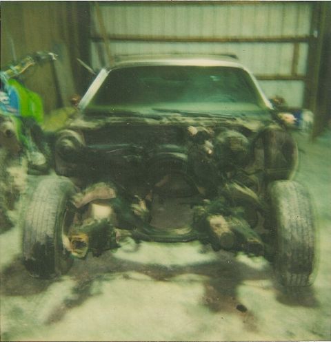 1978 Pontiac Trans Am - This disassembled vehicle's front end is visible, with its engine compartment open and tires mounted. A dirt bike is partially seen to the…
