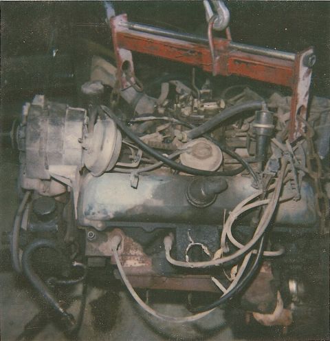 1978 Pontiac Trans Am - Engine assembly with various components and hoses, being lifted by a red engine hoist.