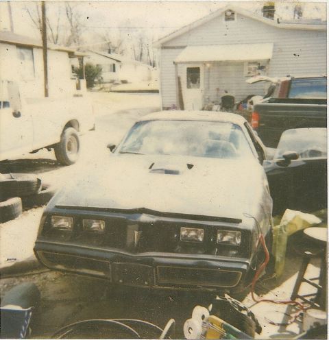 1978 Pontiac Trans Am - A black Pontiac Firebird is parked in a driveway next to a white pickup truck and a house.