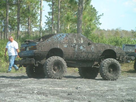 1995 Ford Bronco - A heavily mud-covered vehicle with oversized tires sits in a muddy outdoor area.