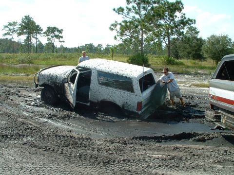 1995 Ford Bronco - Two men attempt to free a white 1995 Ford Bronco that is deeply stuck in mud.