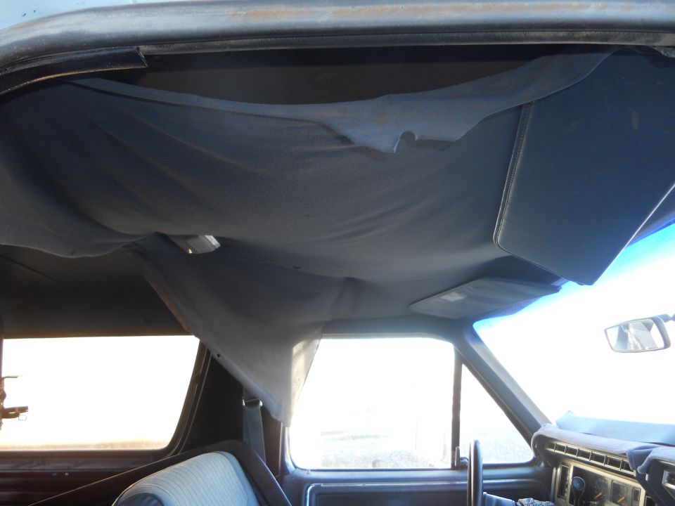 Interior shot of a vehicle showing a detached headliner and sun visors