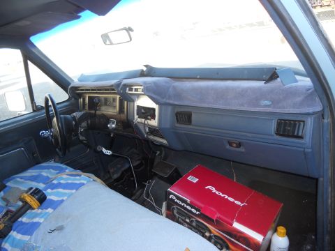 1986 Ford Bronco - The interior of this blue vehicle shows a dashboard and steering wheel, with a Pioneer audio system box on the passenger side.