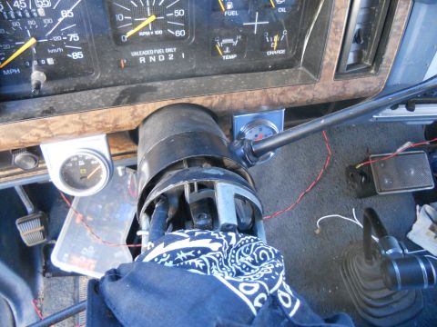 1986 Ford Bronco - The interior of a vehicle shows a dashboard with multiple gauges and a steering column with exposed wiring.