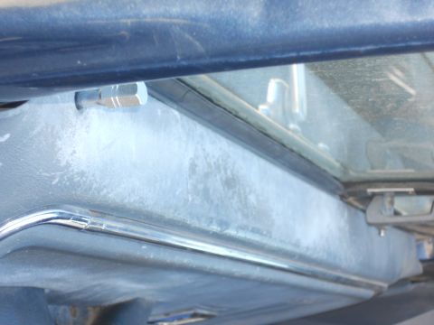 1986 Ford Bronco - The interior of a vehicle shows a dusty dashboard with a chrome accent and a visible bolt.