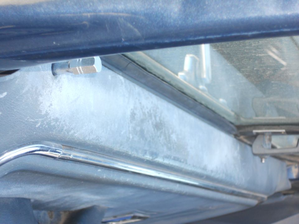 Close-up of a dusty vehicle dashboard with a chrome trim piece and a bolt visible