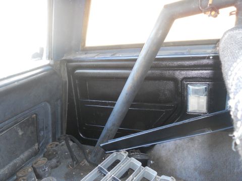 1986 Ford Bronco - The interior of a vehicle shows a roll cage and a watermark from Supermotors.net.