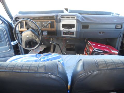 1986 Ford Bronco - The interior of a 1986 Ford Bronco shows the dashboard, steering wheel, and a Pioneer stereo box on the passenger side.