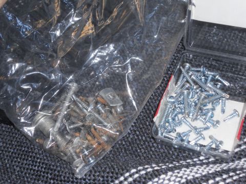 1986 Ford Bronco - A collection of various screws and fasteners are shown in a plastic bag and a small container.