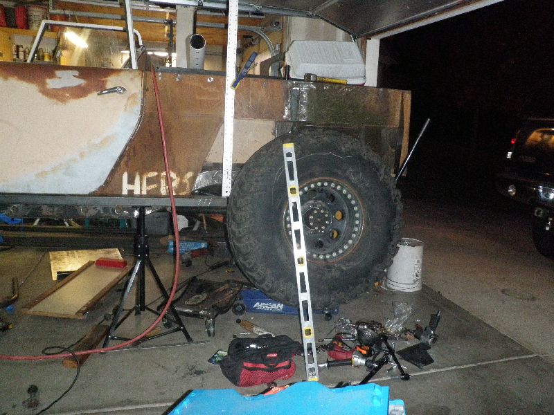 Custom vehicle body with large tire, being worked on in a garage. Text 'HFR' is visible on the side