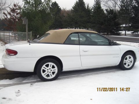 1984 Chevrolet C/K Pickup - A white convertible with a tan top is parked on a snowy surface, with the Chrysler logo visible on its side.