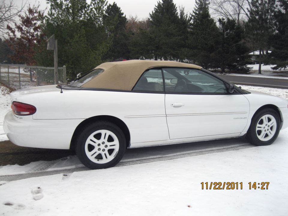 White convertible with tan top parked in snow. "Chrysler" badge visible on the side