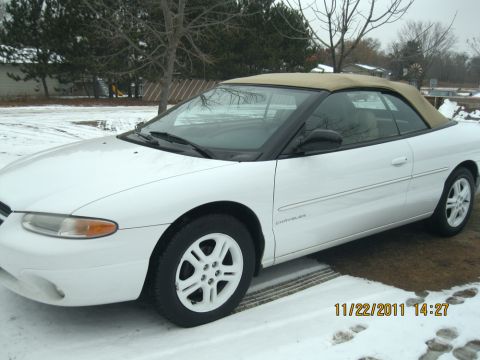 1984 Chevrolet C/K Pickup - A white convertible with a tan top sits in a snowy area, with tire tracks visible on the ground.