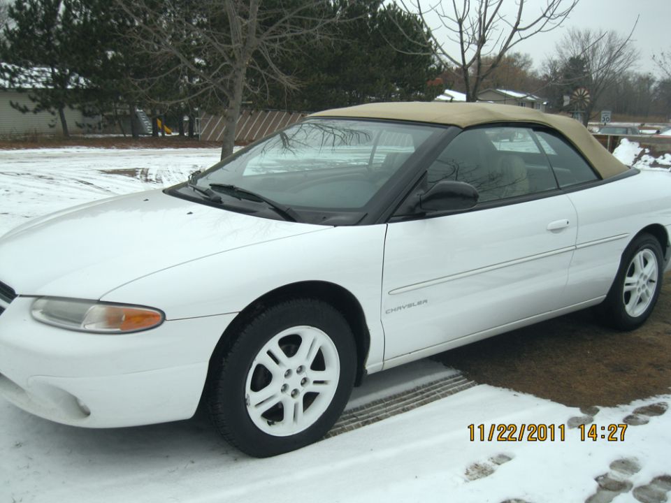 White convertible parked in snow. The word "CHRYSLER" is visible on the side