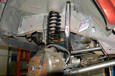 1986 Ford Bronco - Close-up view of vehicle suspension and brake parts, with a bag of hardware attached to the frame.