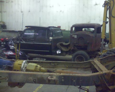 1978 Chevrolet C/K Pickup - Several vehicles and parts are stored indoors, including a rusty truck cab and a black SUV.