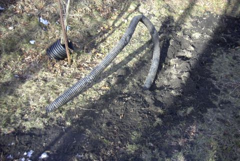 1997 Ford Taurus - Corrugated drain pipe on the ground, partially buried in dirt and grass.