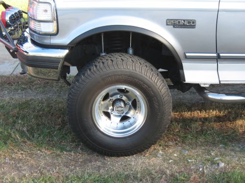 1994 Ford Bronco - Close-up of the front driver's side wheel and fender of a silver Ford Bronco XL.