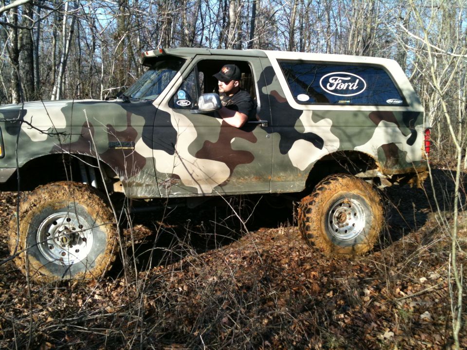 1995 Ford Bronco with camouflage paint driving off-road