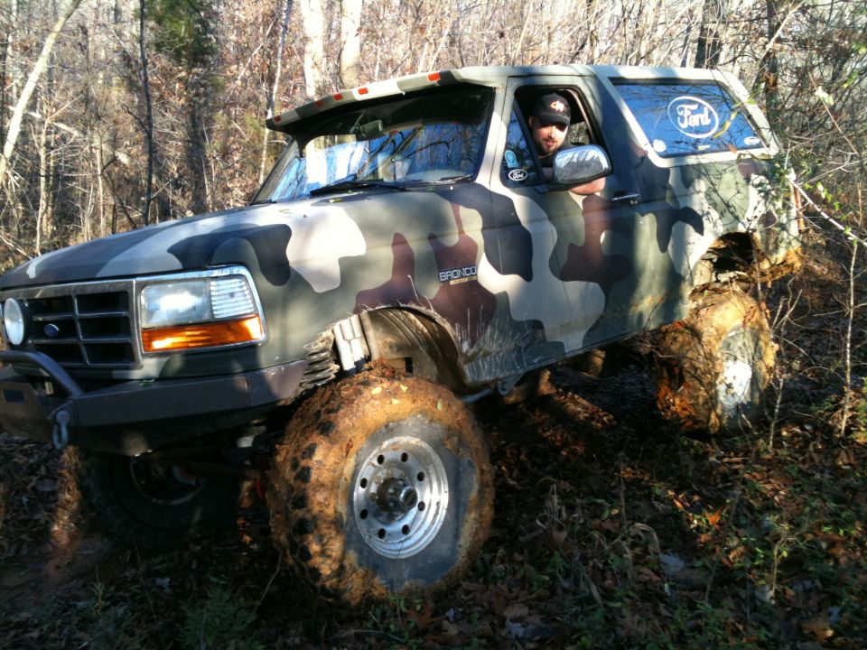 1995 Ford Bronco with camouflage wrap on muddy trail