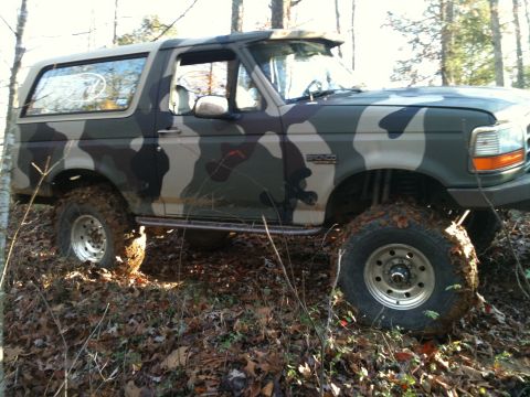 1995 Ford Bronco - Camouflaged 1995 Ford Bronco navigating a muddy, wooded trail.