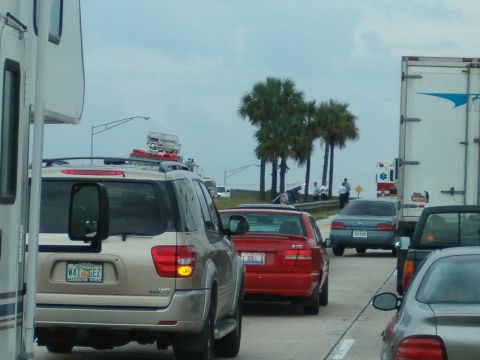 1991 Ford Bronco - A tan SUV is seen from the rear in heavy traffic, with a large trailer mirror attached.