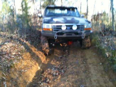 1995 Ford Bronco - This 1995 Ford Bronco navigates a challenging muddy path through a wooded area.