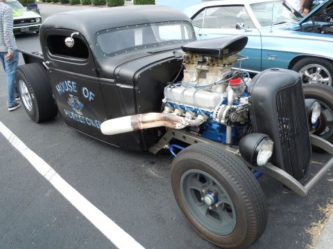 1982 Chevrolet Camaro - A custom black hot rod truck with a prominent engine and "House of Hot Rods" lettering is parked next to other vehicles.