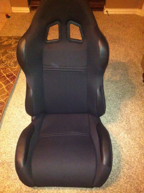 1991 Ford Bronco - A black racing car seat is shown from the front, resting on a carpeted floor.