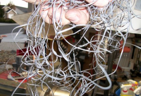 1996 Ford Bronco - Metal shavings are tangled in a person's hands, with a workshop in the background.