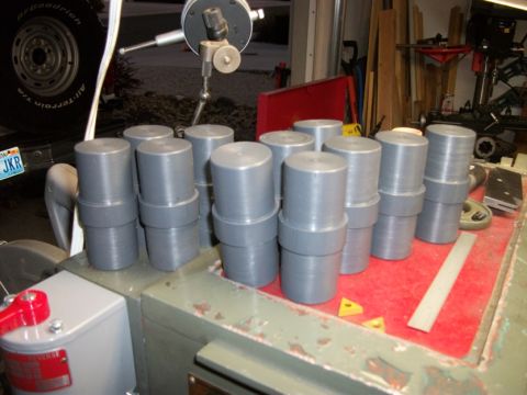 1996 Ford Bronco - Gray cylindrical machine parts are arranged on a red surface, with a tire and license plate in the background.