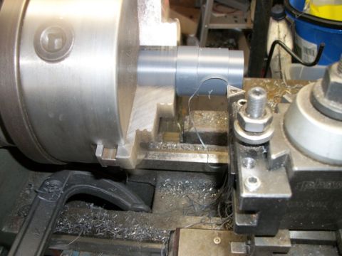 1996 Ford Bronco - A metal rod is being machined on a lathe, with metal shavings visible around the chuck and cutting tool.