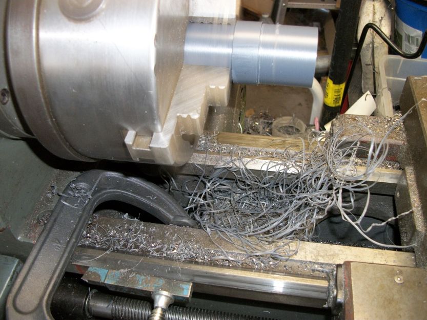 Metal shavings piled up on a lathe bed next to a chuck holding a pipe