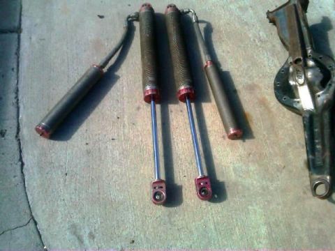 1986 Ford Bronco - Close-up of automotive parts including shock absorbers and a differential housing laid out on a concrete surface.