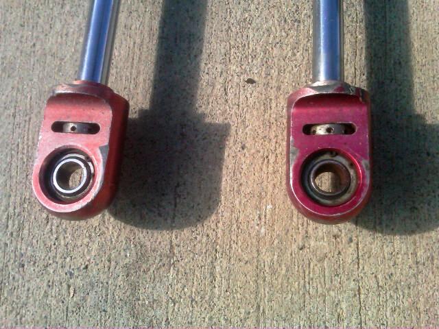 Two red shock absorber ends with visible bearings and metal shafts