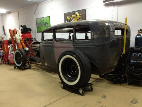 1986 Ford Bronco - A vintage hot rod sedan, likely a 1931 Ford Model A, sits in a workshop with various tools and equipment around it.