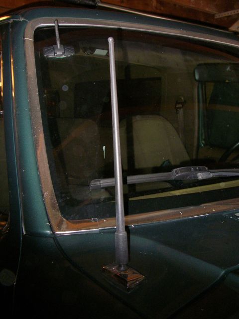 1990 Ford Bronco - Close-up of a car's antenna mounted on the hood, with a view of the windshield and interior.