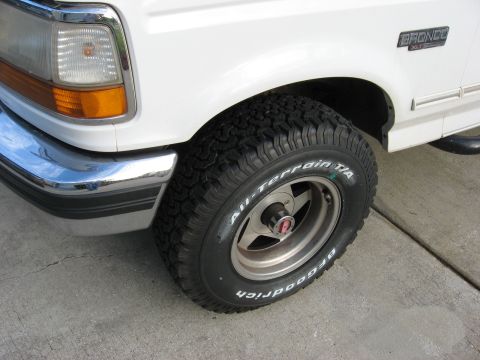 1994 Ford Bronco - The front passenger side of a white Ford Bronco, showing the tire and fender detail.