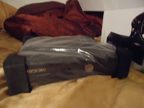 1992 Nissan 240SX - An Xbox 360 console is shown, partially covered in plastic, with a red blanket and a box nearby.