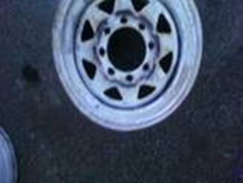 1989 Ford Bronco - A single wheel is shown close-up against a dark, textured surface.