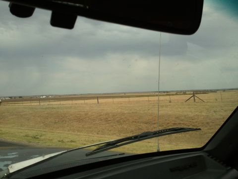 1989 Ford Bronco - Driving through a wide-open, grassy area with a fence line in the distance under an overcast sky.