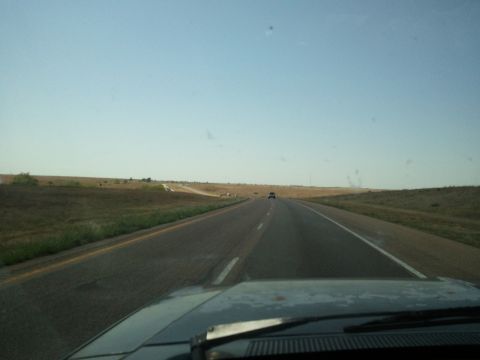 1989 Ford Bronco - View from inside a vehicle driving on a highway with another car in the distance under a clear blue sky.