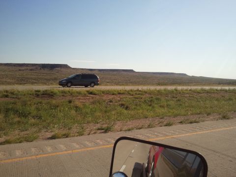 1989 Ford Bronco - Minivan travels down a highway with a desert mesa in the distance.