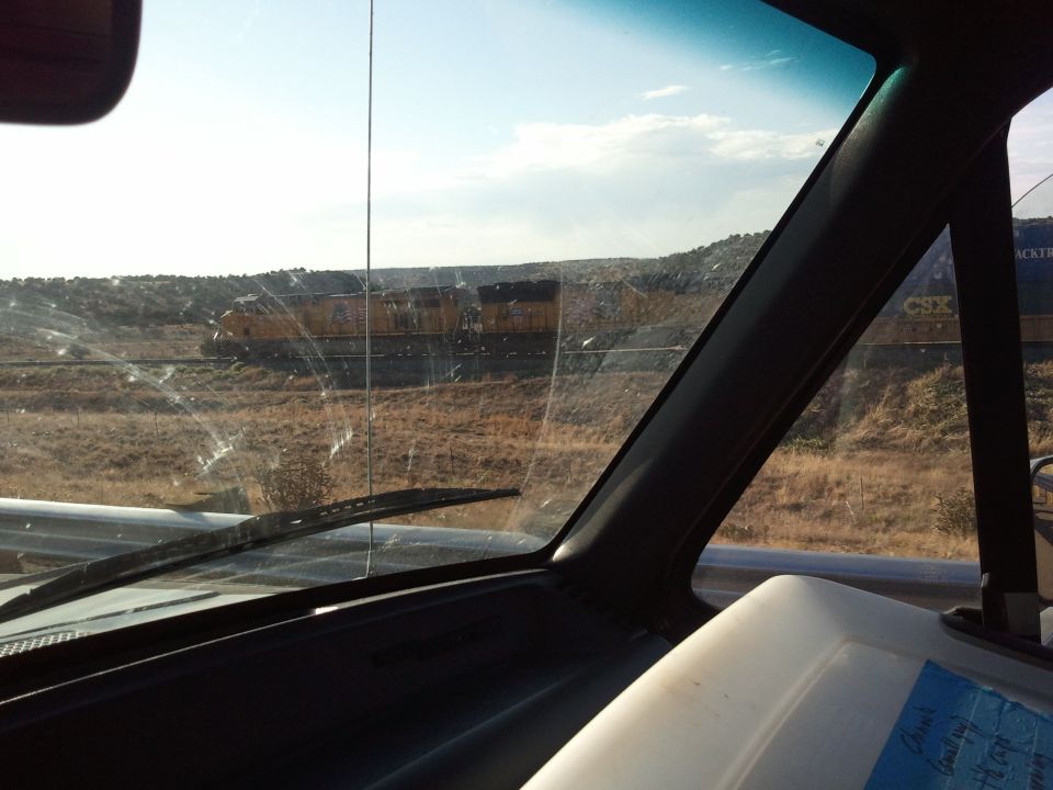 Interior view of a vehicle looking out at a train on the tracks