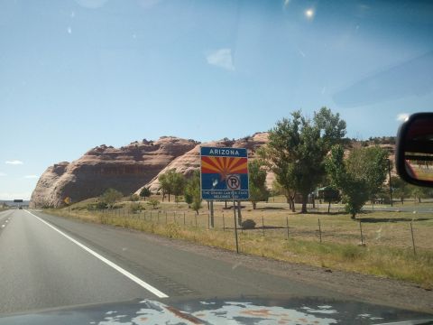 1989 Ford Bronco - Driving into Arizona, the Grand Canyon State welcomes you with a sign and scenic red rock cliffs.