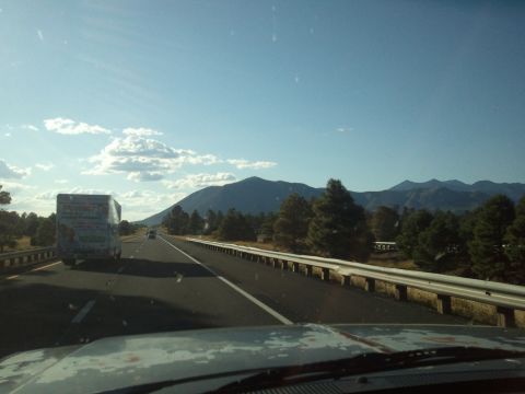 1989 Ford Bronco - View from inside a vehicle on a highway, with a box truck ahead and mountains under a blue sky.