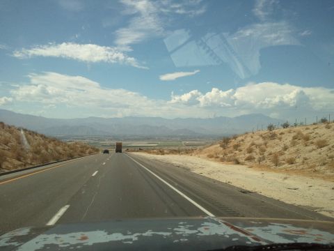 1989 Ford Bronco - Driving on a highway through a desert landscape with mountains in the distance under a cloudy sky.