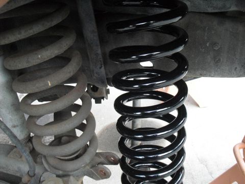 1986 Ford Bronco - Comparison of a new black coil spring and an old, rusty coil spring, likely for a vehicle suspension upgrade.