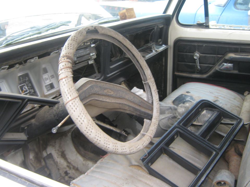 1978 Ford Bronco interior showing cracked dashboard, worn steering wheel cover, and loose trim pieces