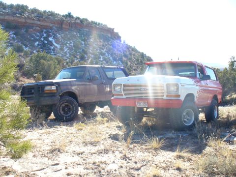 1979 Ford Bronco - Two Ford Broncos, one a 1979 model, are parked off-road in a desert landscape.